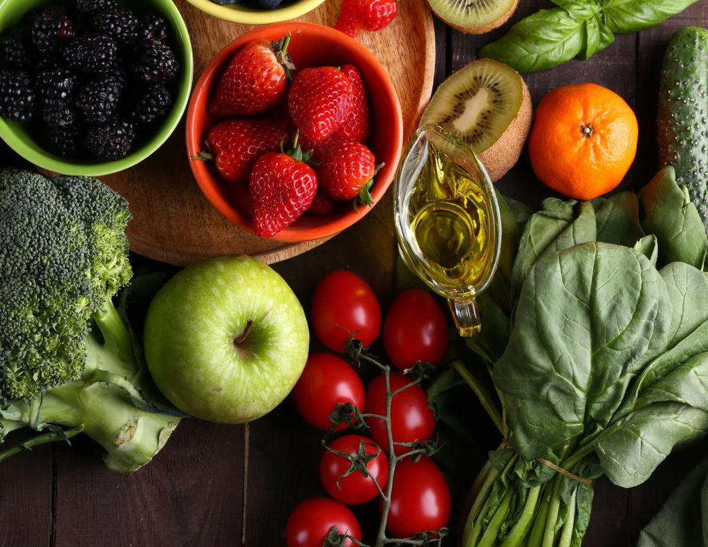 Apples, strawberries, blueberries, broccoli, spinach, tomatoes and other fruits and vegetables on a dark wood table.