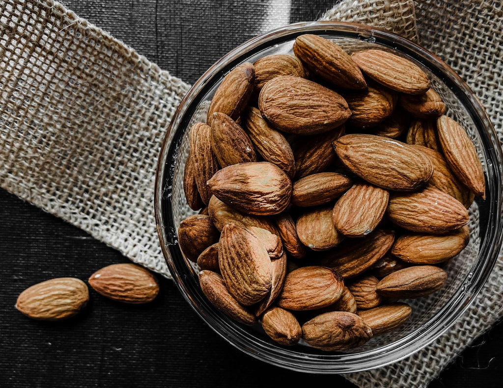 A glass bowl of whole almonds.