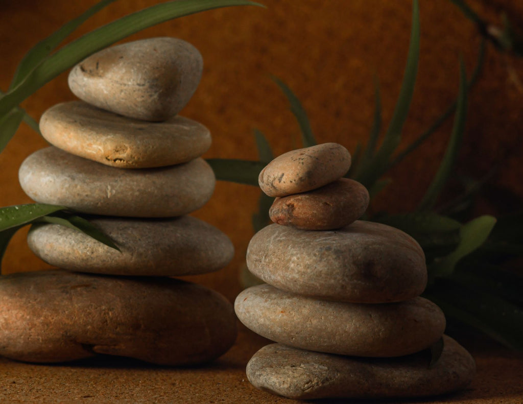 Two piles of rocks, both rising in descending order from largest to smallest stand side by side. The colors of the stones are grey, brown, and taupe.