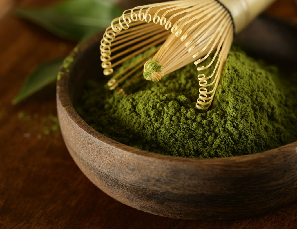 A pile of vibrant green, powdered matcha in a dark wood bowl. 