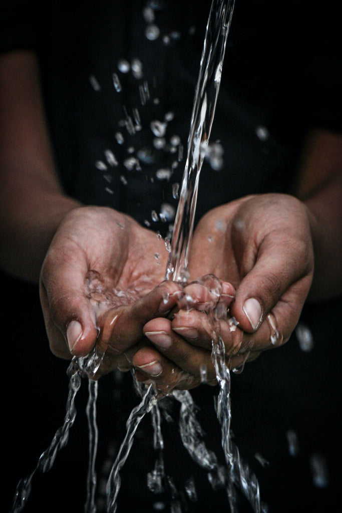 Clear water flows is poured into a pair of cupped, brown-skinned hands.