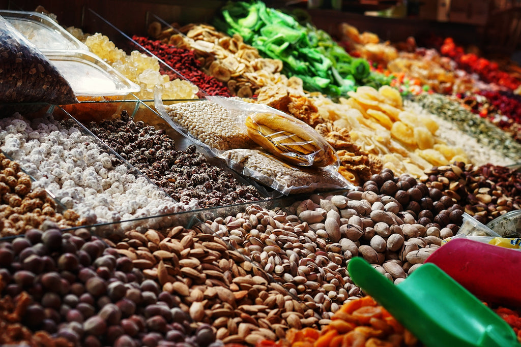 A display of a variety of nuts, dried fruits, and fresh herbs at a market.