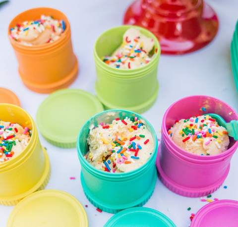 5 x different colour Re-Play Snack Stacks with vanilla icecream and sprinkles on top sitting on a white tablecloth