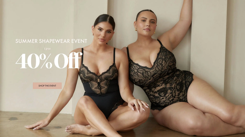 Two women sitting while wearing pinsy shapewear bodysuits in black lace
