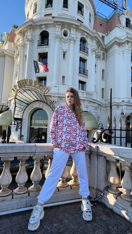 Czarina Sasha (@sashastarynets) is wearing a white bomber jacket with Red Czar text for Czar Clothing in Nice, France.