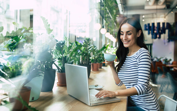 Woman at a coffee shop with plants by the window