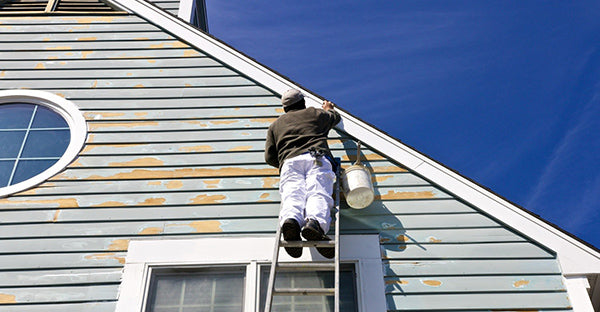 man preparing paint on exterior of house