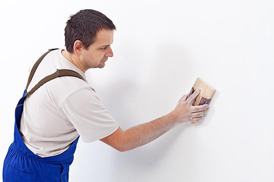 man sanding wall for paint preparation