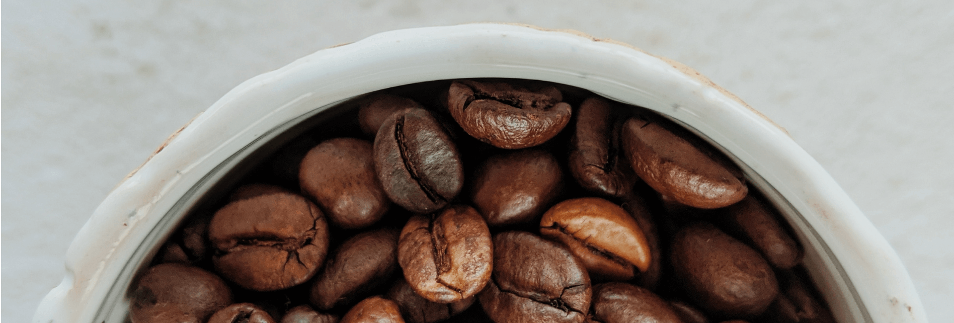 dark roasted coffee beans in a white bowl ready to be ground