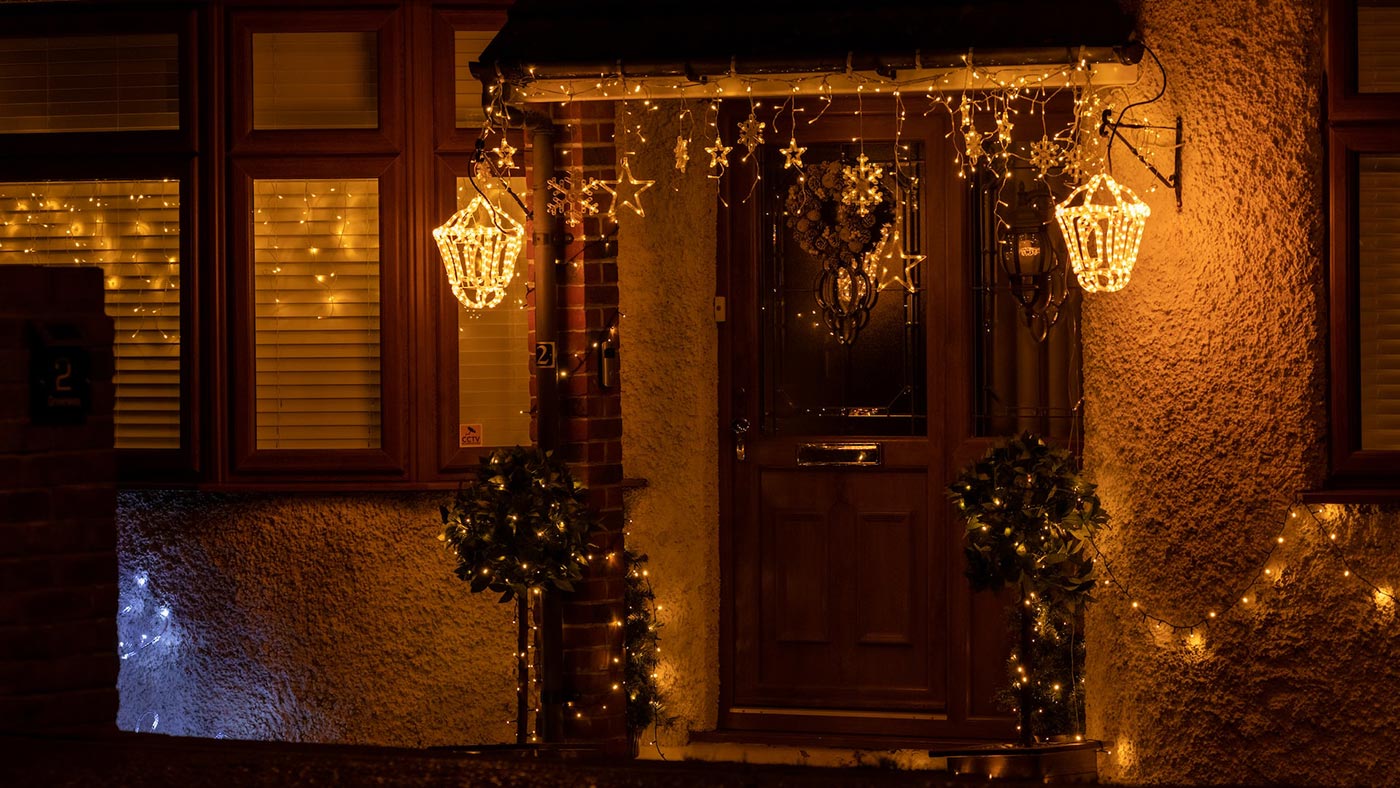 Karácsonyi fényfüzérekkel díszített ház bejárat.