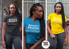 Black woman wearing black, blue and yellow shirt that reads "Beauty Brains and about God's business."