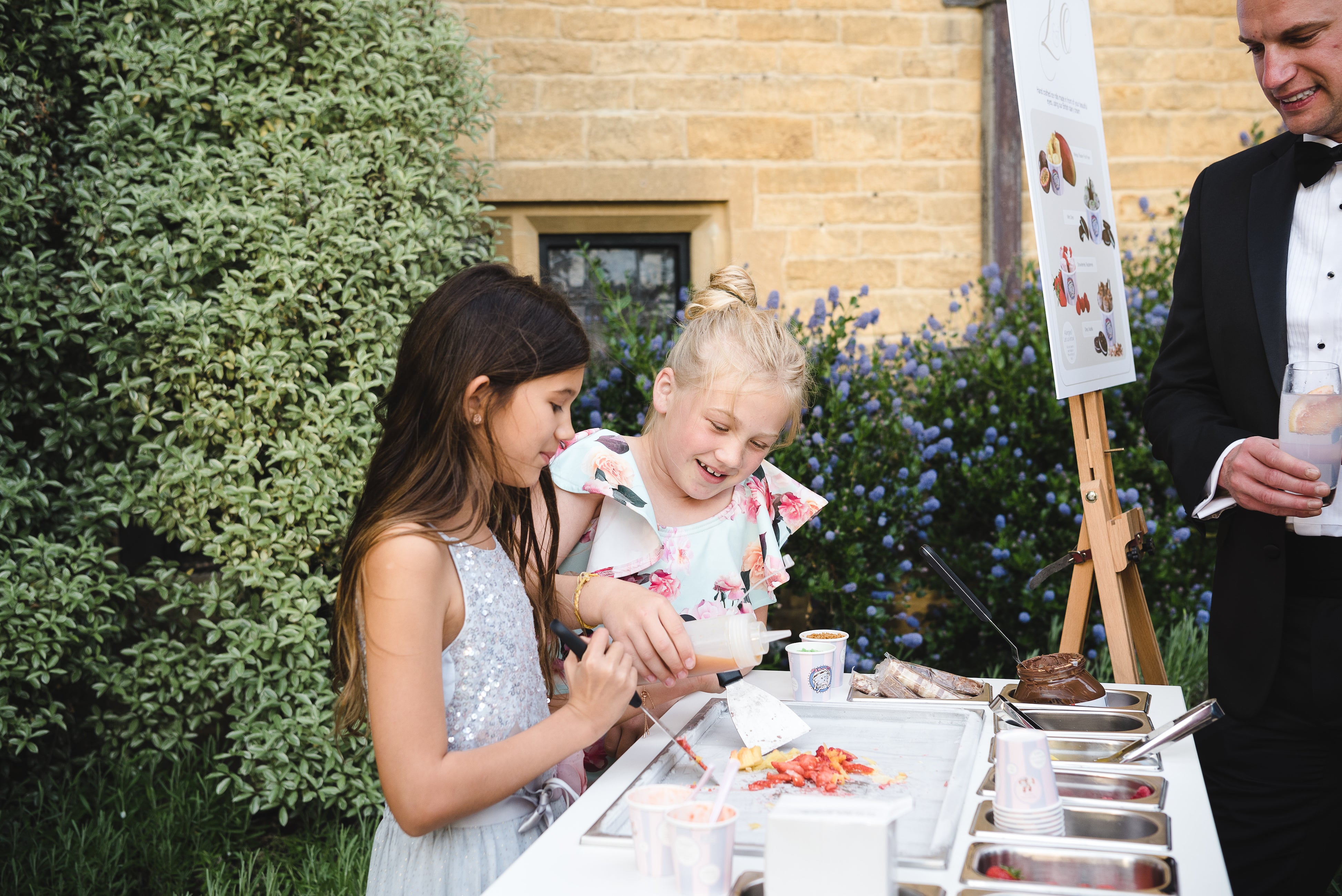 2 young girls who are guests of the wedding trying to make their own custom ice cream rolls