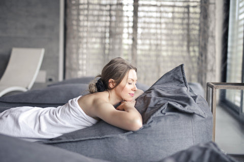 Woman lying on her stomach in a towel on the bed, looking content and relaxed