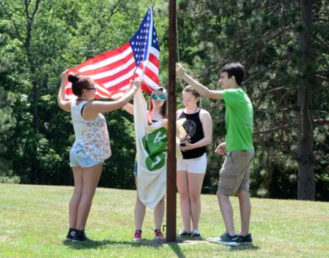 Kids practice honorable handling of the flag at summer camp.