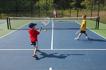 July 26, 2011 Photographs from Western Racquet Club in Elm Grove where they are unveiling tennis courts with smaller dimensions that are made for kids 10 and under.  United States Tennis Association is making changes that also include the sizes of racquets and balls.  Here Jodi Keller of Wauwatosa (center) plays tennis  on one of the reduced size courts with sons Charlie Keller, age 5 (red shirt at left) and Jack Keller age 9 (right in yellow). 