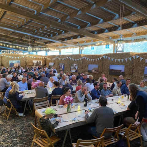 Cheesemakers feasting at long tables in a barn on Ulceby Grange Farm