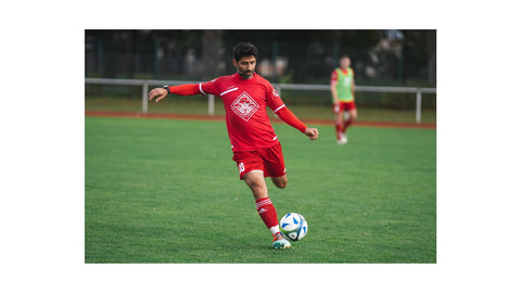 A Guy Wearing A Red Jersey is Playing Soccer and He is About to Kick the Ball