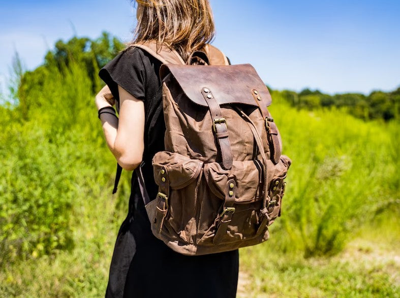 Eine Frau trägt einen braunen Rucksack aus gewachstem Canvas und Leder – woosir