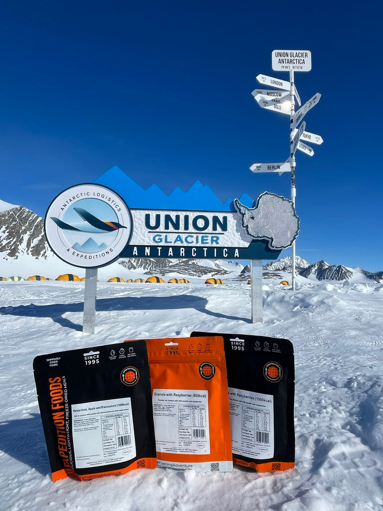 meal pouches on the snow near a camp site of multiple tents.