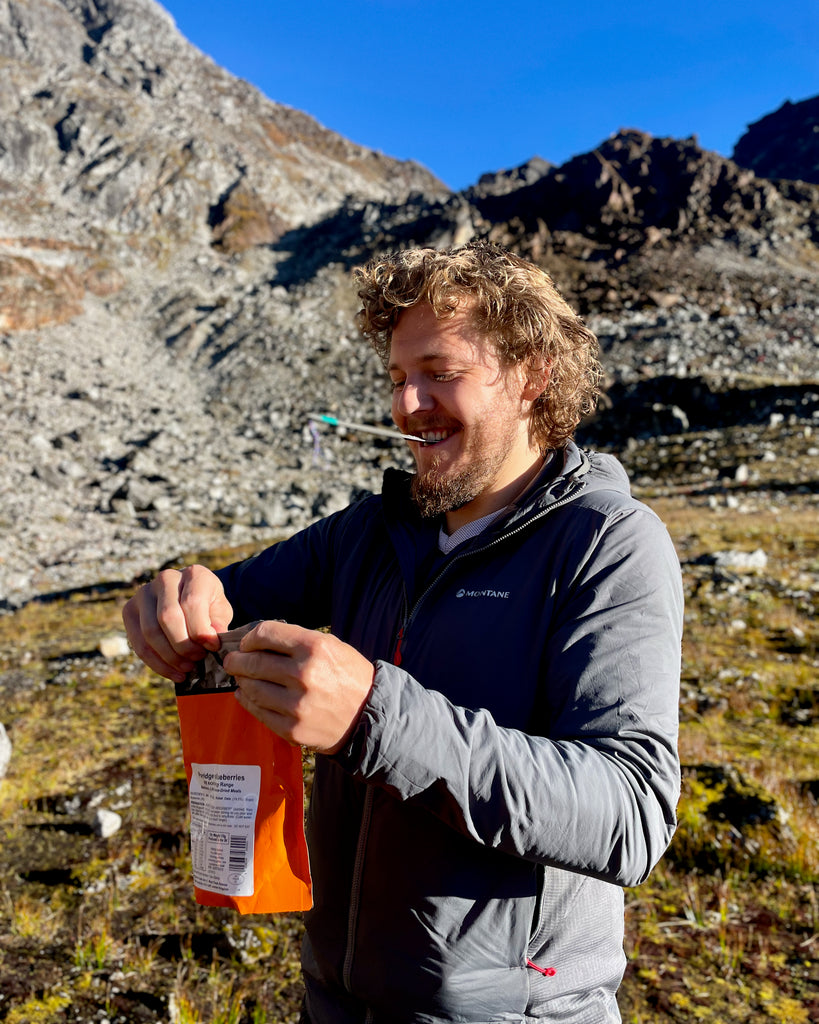 Person holding Expedition Foods meal in the mountains getting ready to eat it.