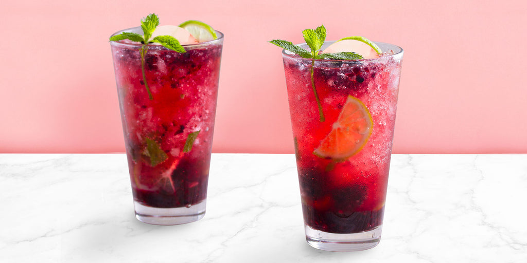 An image of two Blackberry Mojitos against a pink background.