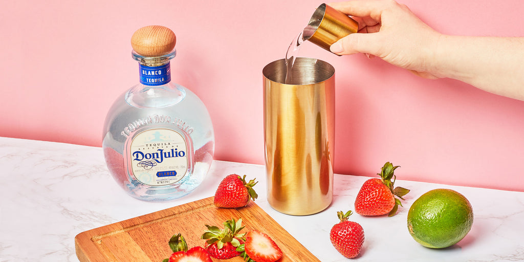 An image of someone pouring Strawberry Margarita ingredients into a cocktail shaker.