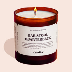 A masculine looking candle that reads Bar Stool Quarterback