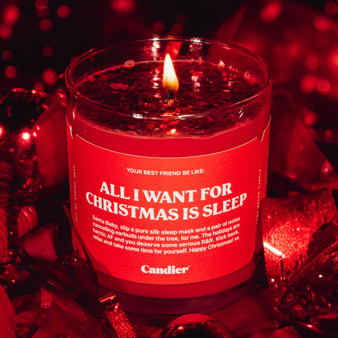 A festive red candle with glitter and a label that reads All I Want For Christmas Is Sleep