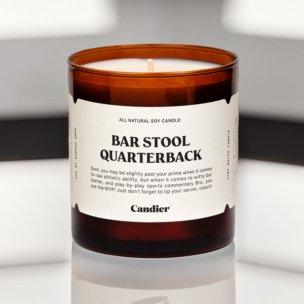 A brown glass candle with a label that reads Bar Stool Quarterback