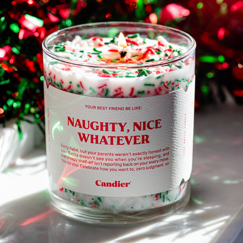 A Christmas themed candle with a label that reads naughty nice whatever