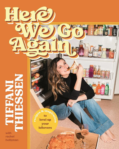 A cook book titled Here We Go Again with a picture of Tiffani Thiessen eating pizza