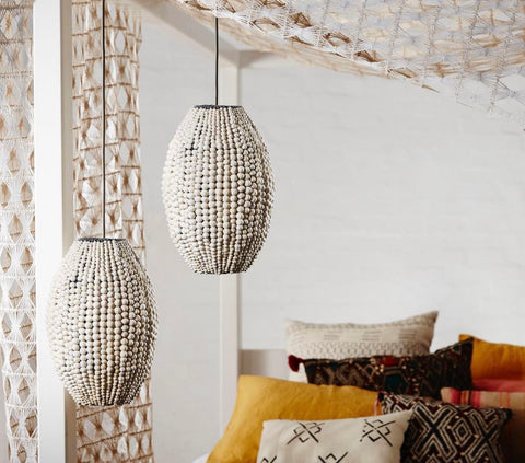 gorgeous natural pendant lights above a bed covered in shells