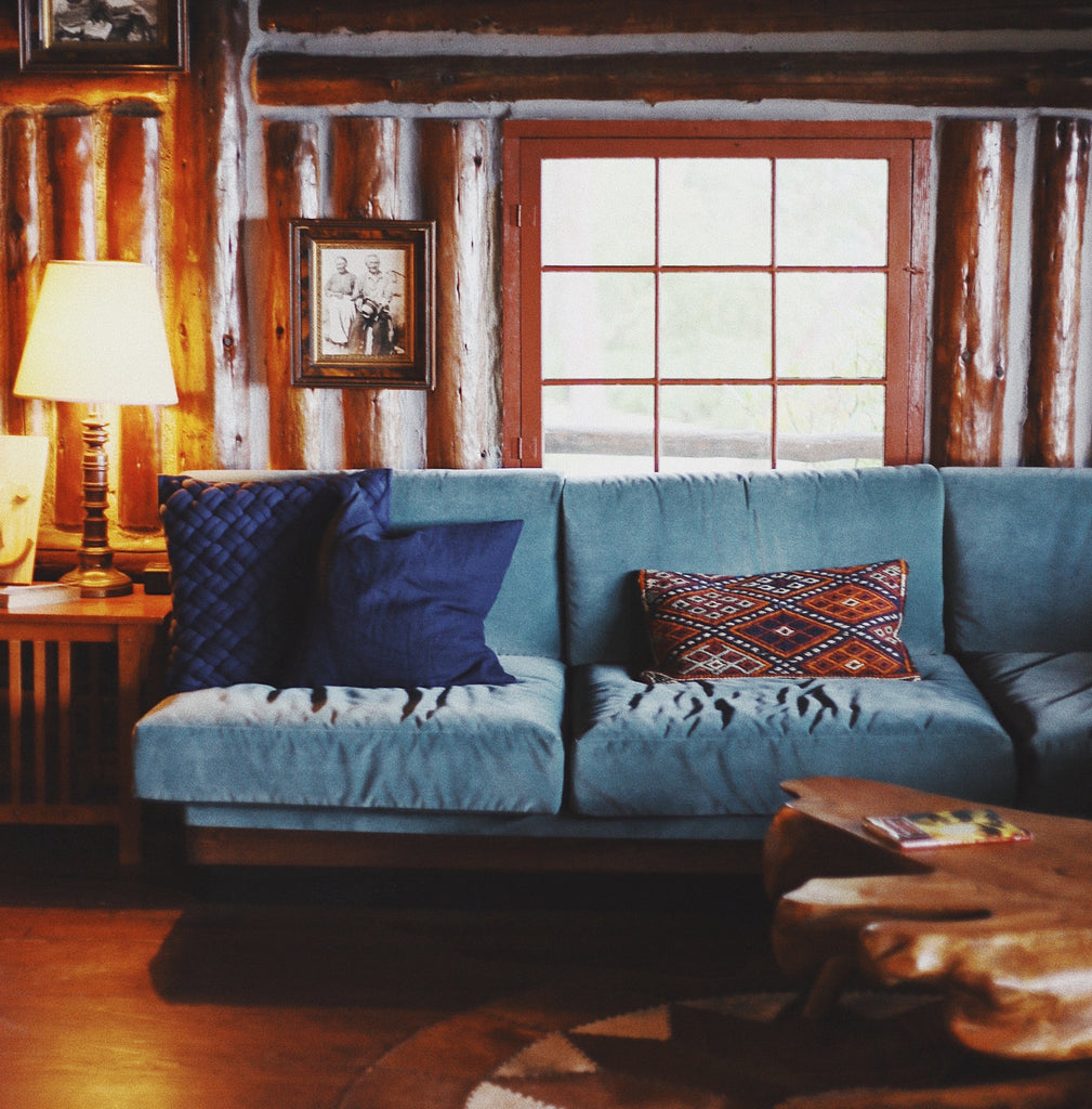 Chalet style living room with wooden walls and features. A light blue velvet sofa and dark blue cushions