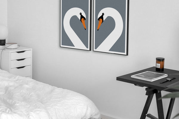 Pair of swans art prints next to a bed