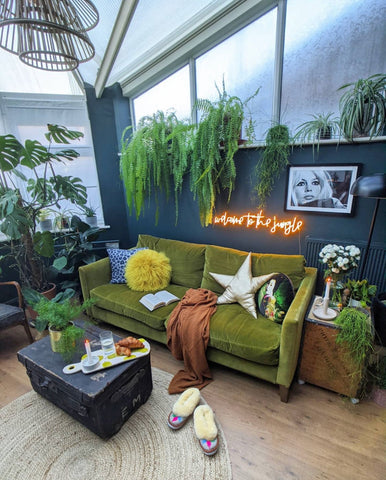 super cool living room with green sofa neon lights and lots of tall plants