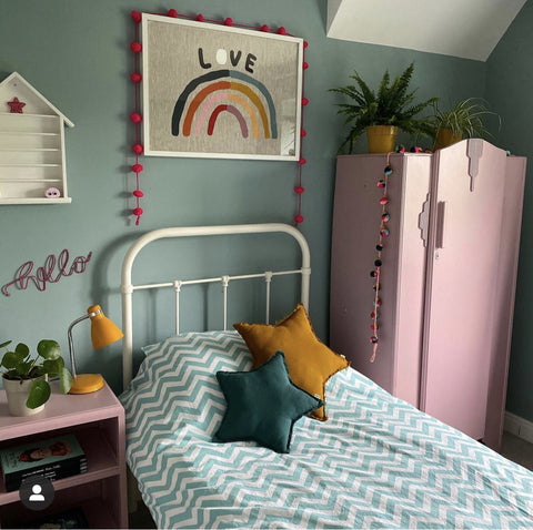 girls bedroom image with a single bed, pink wardrobe, pale green walls and a rainbow art print hung over the bed