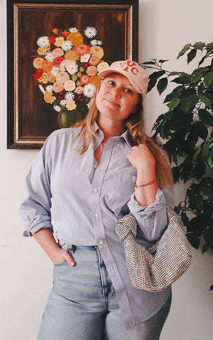 Blue and white button down, baseball hat and sparkly bag