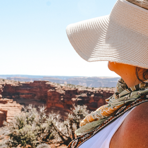 woman looking out over valley in a hat and bandana 