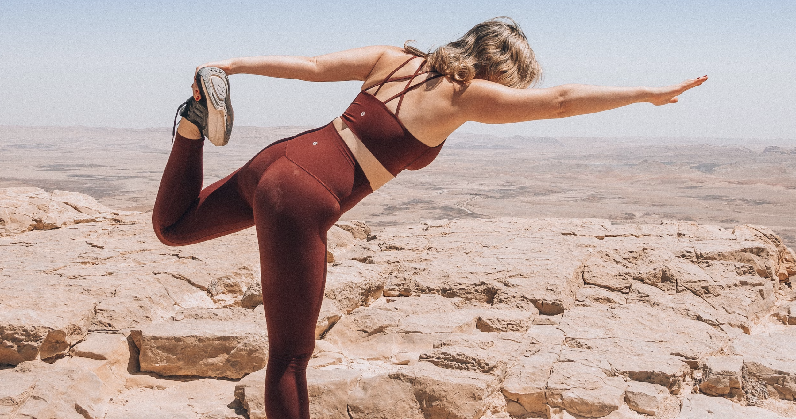 Une consommatrice de compléments alimentaire en train de faire une position de yoga dans un désert.