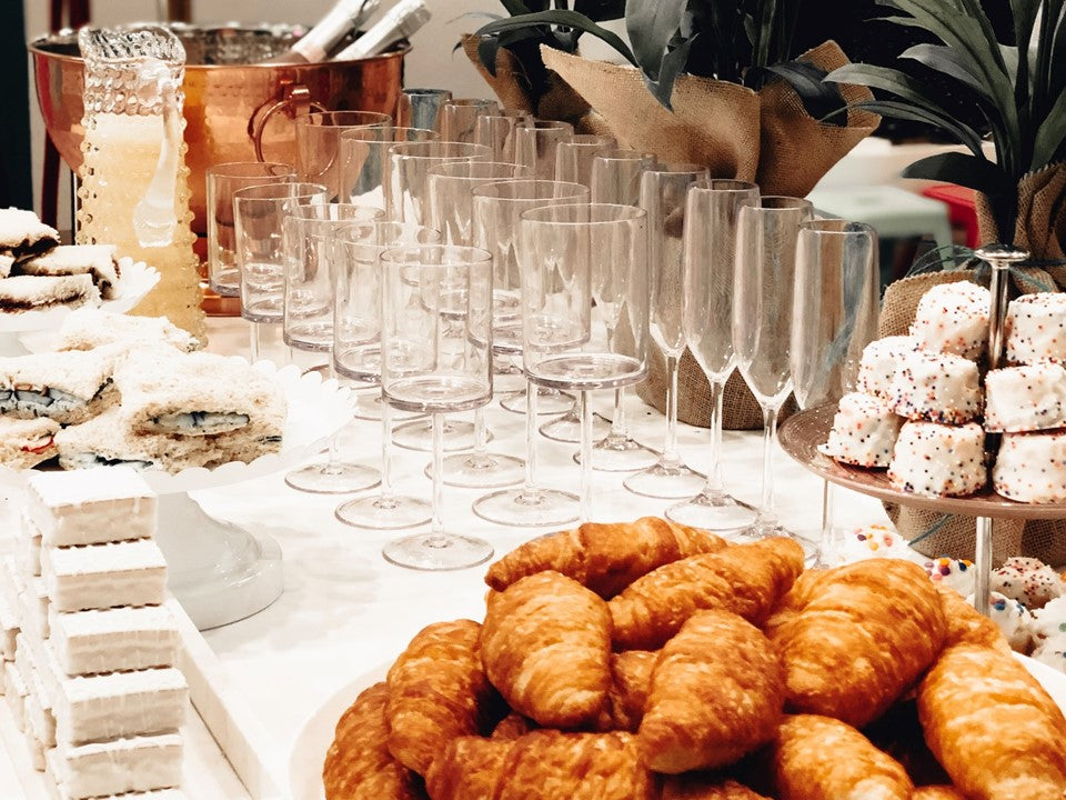 A tablescape of wine glasses, croissants, and other treats