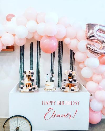 A dessert cart with pink balloons and cupcakes at Waterlemon Kids