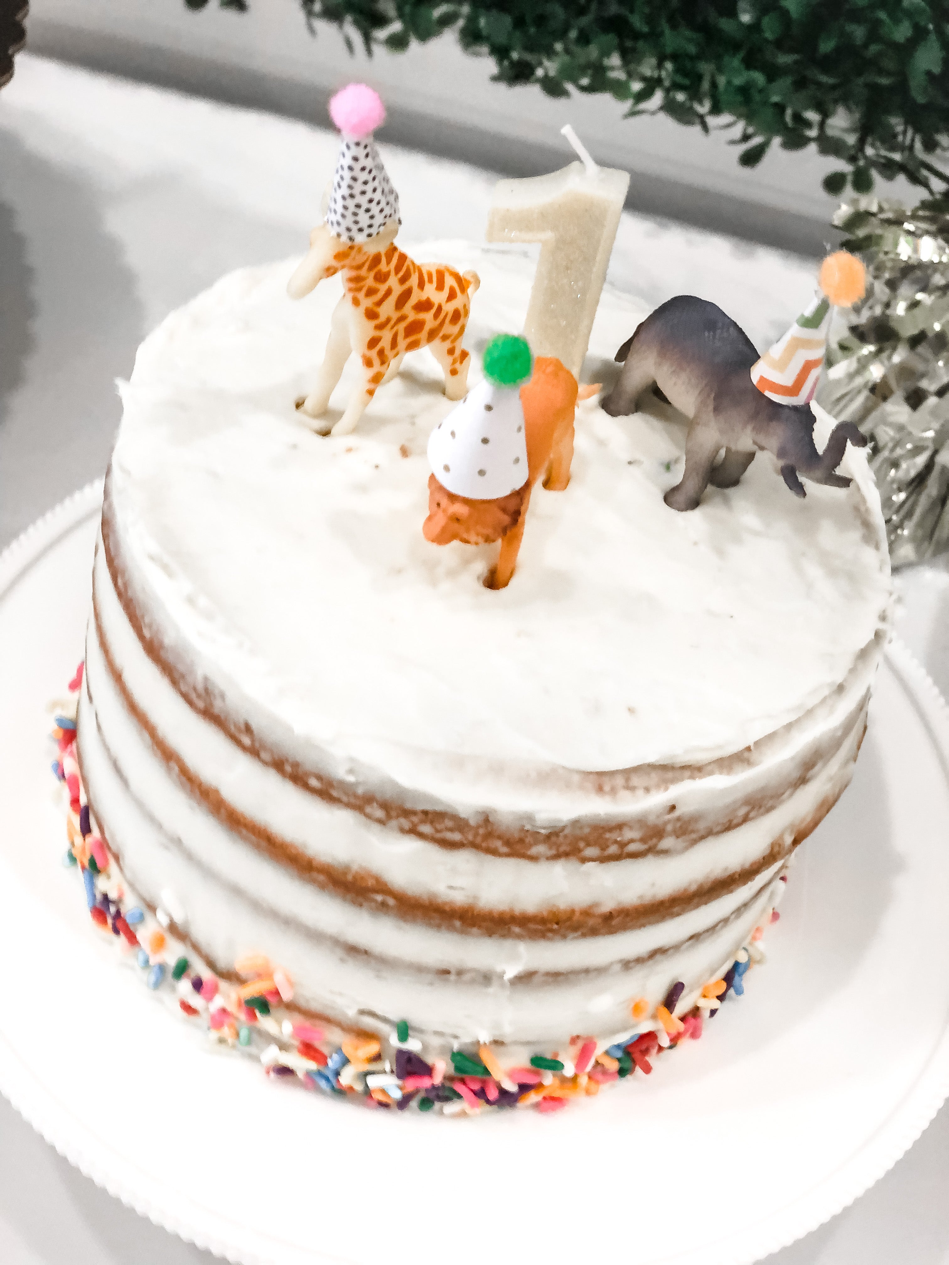 A one year old birthday cake with zoo animals and a Number 1 candle