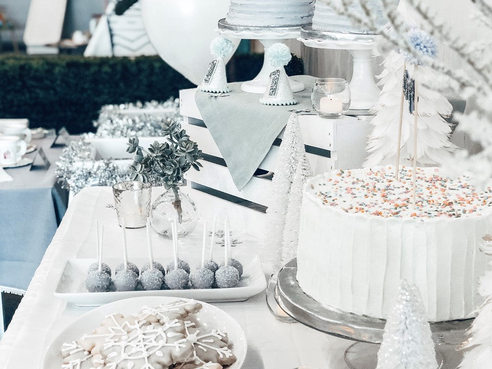 A silver and blue dessert table with cake, cakepops and cookies