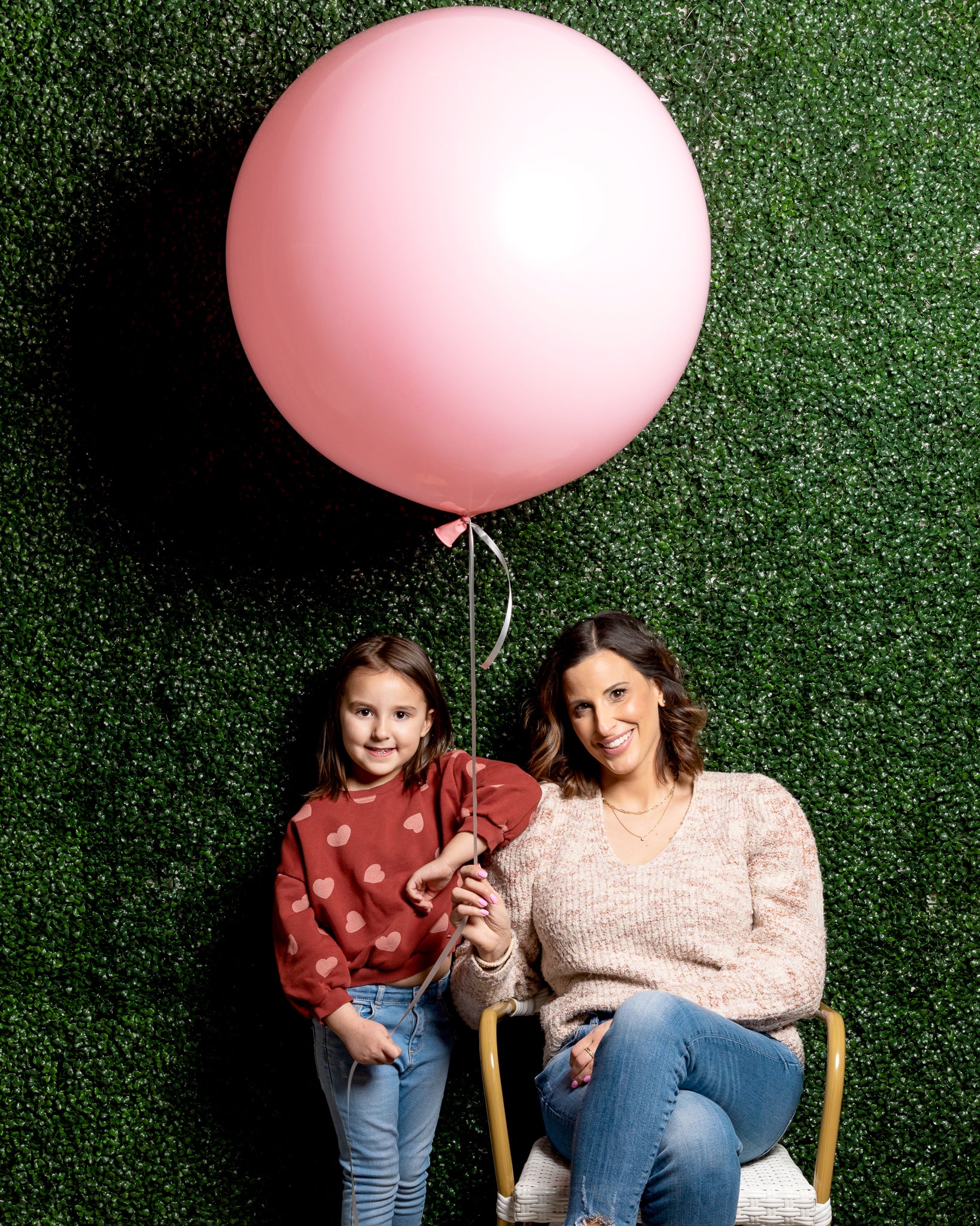 Nina and her daughter in front of the greenery wall at Waterlemon Kids holding a pink balloon