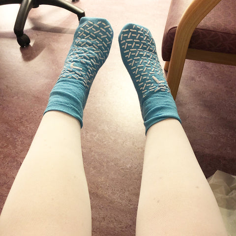 Pair of legs in white surgical stockings with lightblie comfort socks pre-surgery for Endometriosis