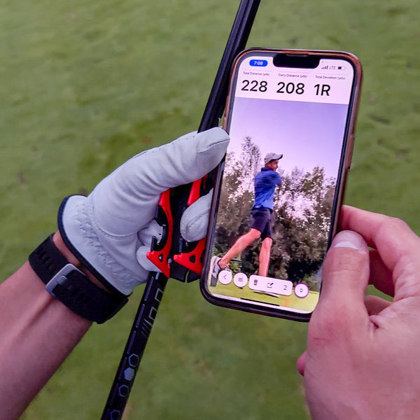 Two hands holding an Iphone with a video showing a man playing golf