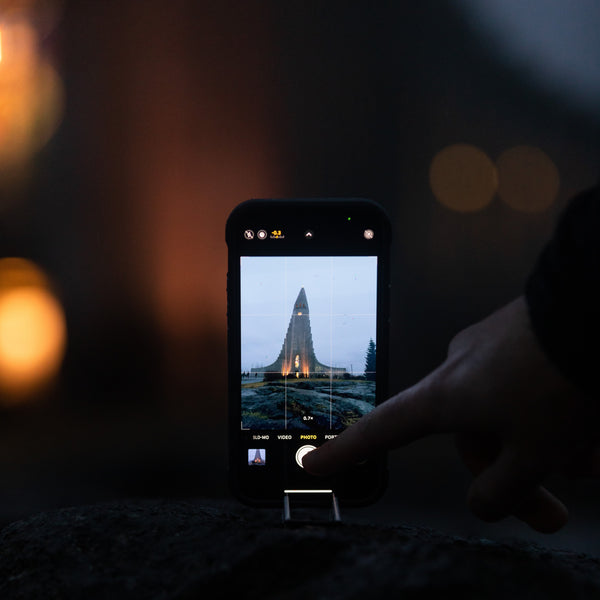 An iphone in a tripod taking a picture of a monument at night