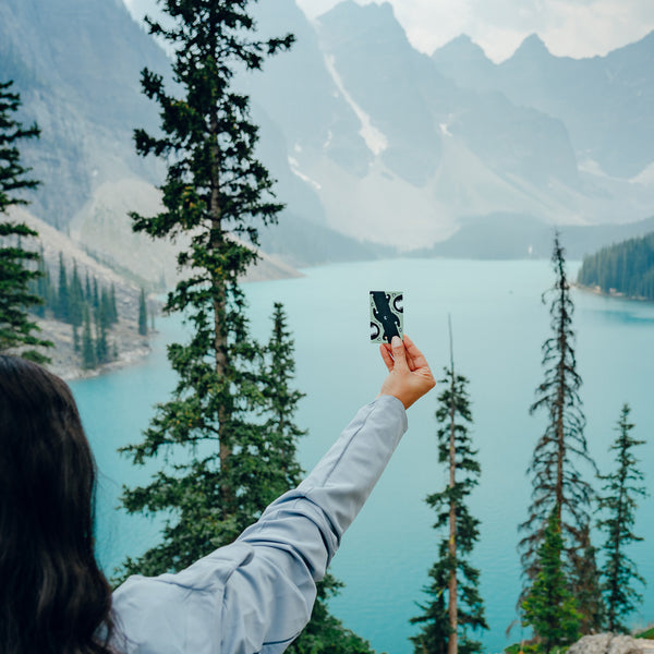 A girl holding a pocket tripod in her hand in front of a lake