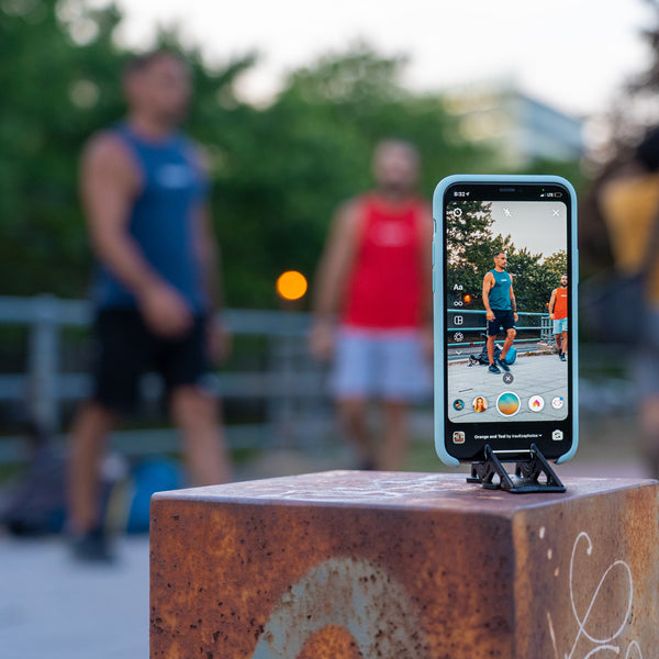An iphone on a tripod stand taking picture of two guys doing gym at the background