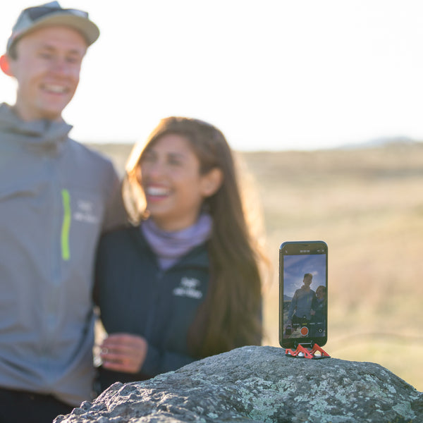 A couple taking a picture of them with an iphone on a tripod